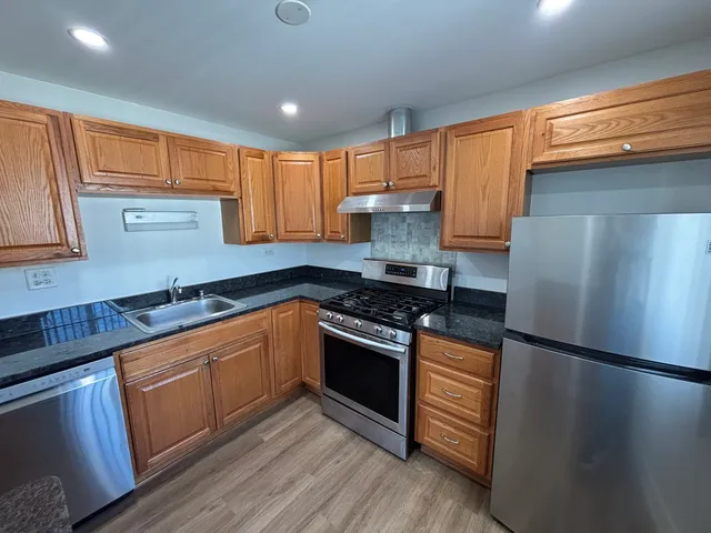 a kitchen with stainless steel appliances granite countertop a stove a refrigerator and a sink