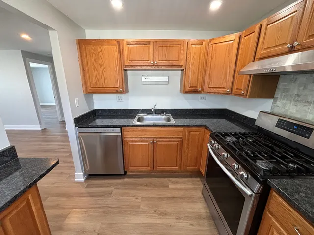 a kitchen with granite countertop a sink a stove and cabinets