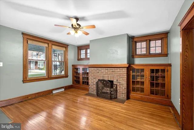 an empty room with windows fireplace and a ceiling fan