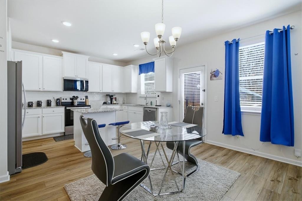 3980 Riverchess Drive Southwest Atlanta, GA 30331 - Photo 10 of 46 a kitchen with stainless steel appliances granite countertop a stove top oven a refrigerator a sink and a dining table with wooden floor