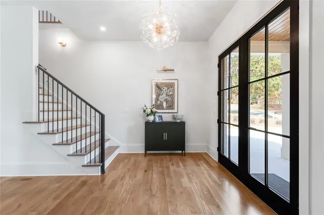 a view of a hallway with wooden floor staircase and living room