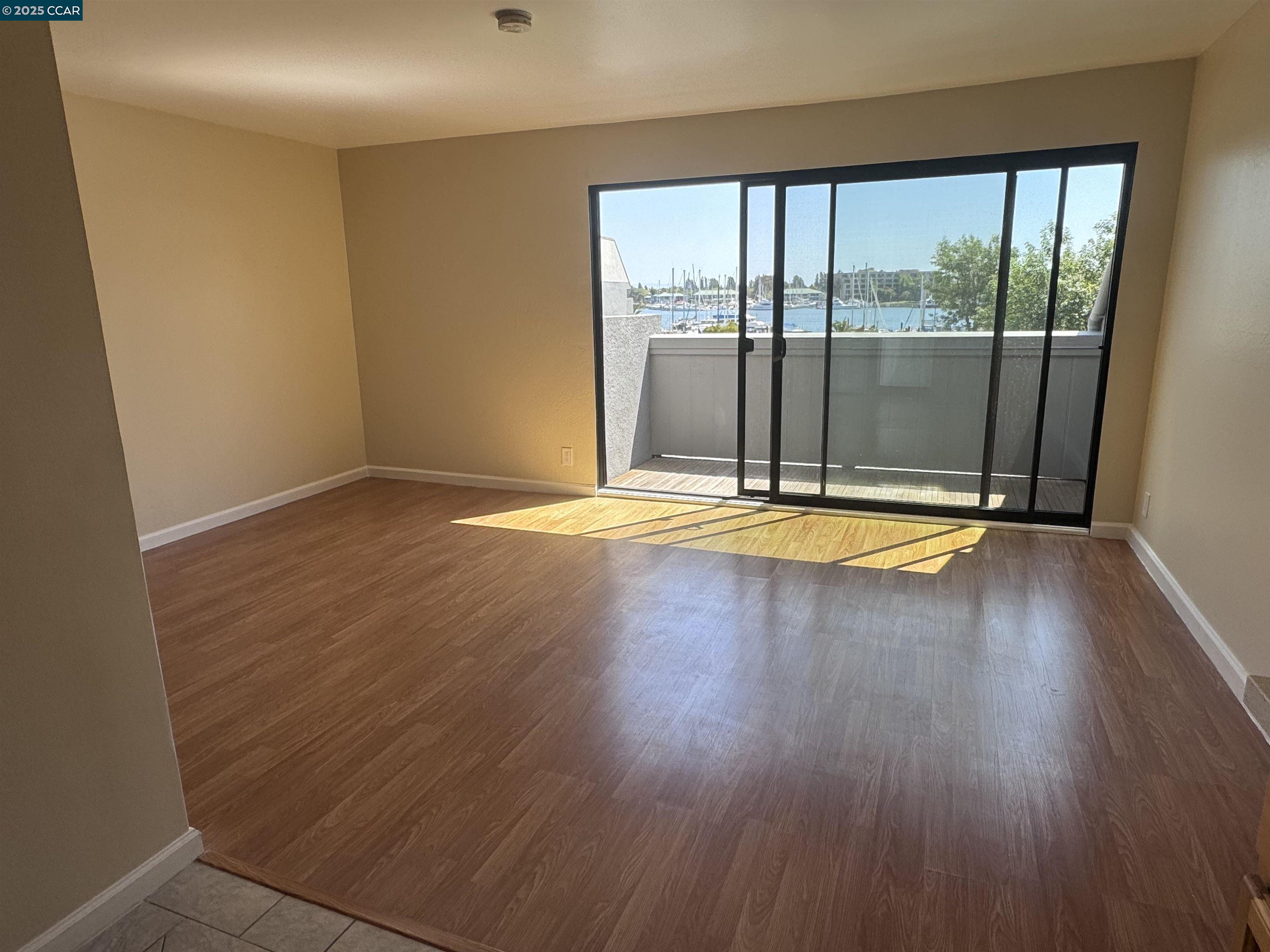 a view of empty room with wooden floor and floor to ceiling window