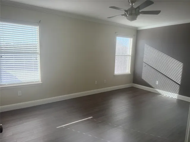 an empty room with wooden floor fan and windows