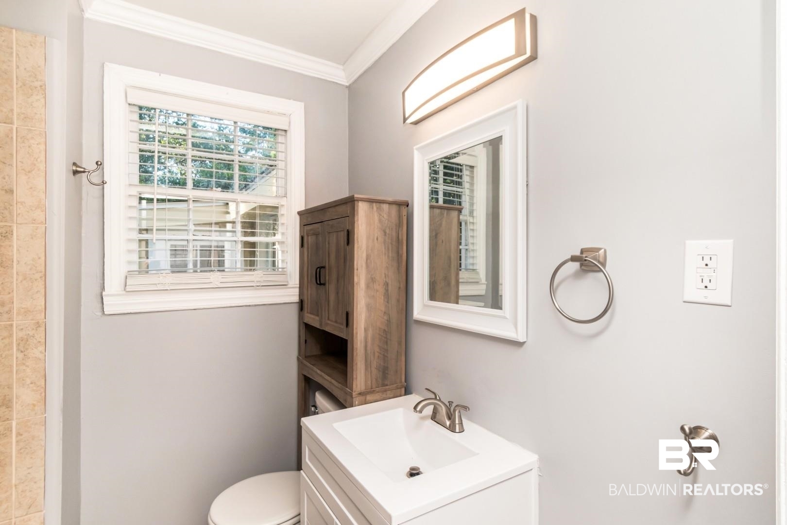 263 Border Drive East Mobile, AL 36608 - Photo 16 of 27 Bathroom featuring a single window with blinds, white vanity with integrated sink, brushed nickel faucet, wall-mounted mirror with white frame, and a wood-finish storage cabinet