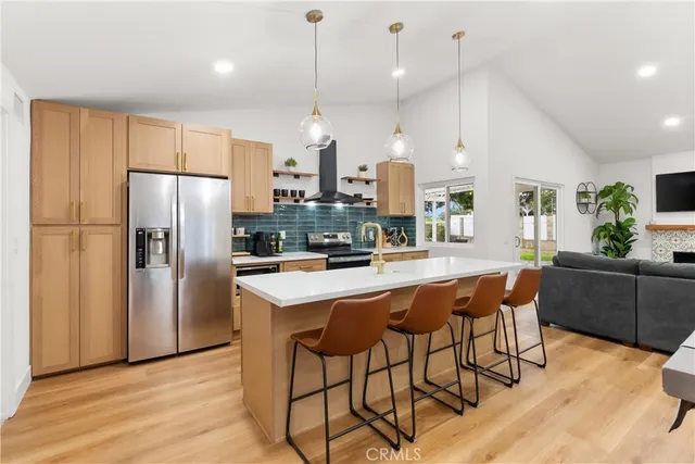 a kitchen with stainless steel appliances granite countertop a refrigerator a stove a sink a dining table and chairs with wooden floor