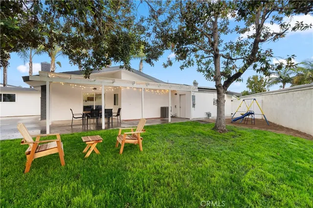 a view of a white house with a yard table and chairs