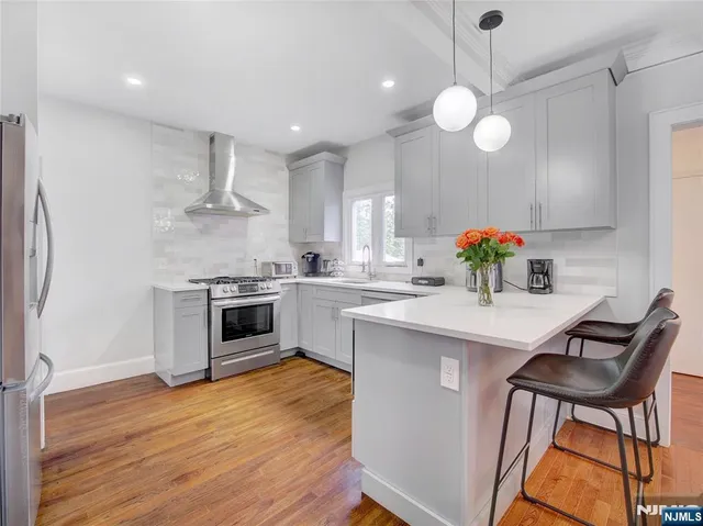 a kitchen with white cabinets stainless steel appliances and wooden floor