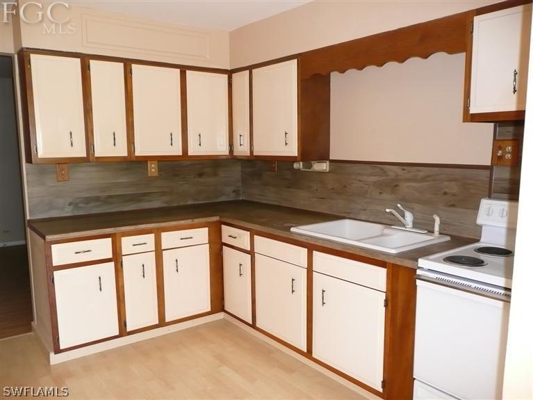 5952 Sailfish Road Bokeelia, FL 33922 - Photo 11 of 20 a kitchen with stainless steel appliances granite countertop a sink a stove and white cabinets