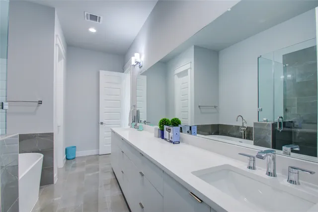 a bathroom with a double vanity sink mirror and bathtub