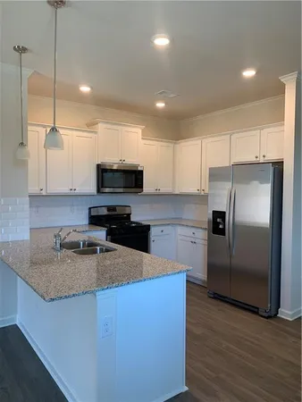 a kitchen with granite countertop a refrigerator a sink a stove a microwave and wooden floor