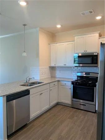 a kitchen with stainless steel appliances granite countertop a stove a sink and a microwave