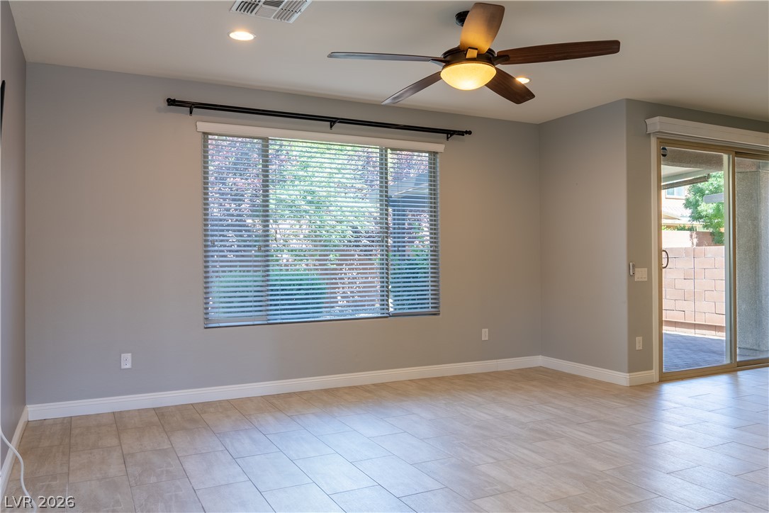11045 Elk Sands Road Las Vegas, NV 89179 - Photo 49 of 67 Plank tile flooring and recessed lighting accent this spacious living area with sliding door access.