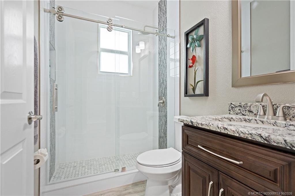 1268 Southeast Kirk Street Stuart, FL 34997 - Photo 17 of 63 a bathroom with a granite countertop sink toilet and shower