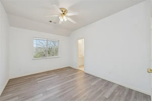 an empty room with wooden floor chandelier fan and windows