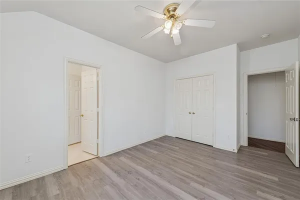 an empty room with wooden floor and ceiling fan
