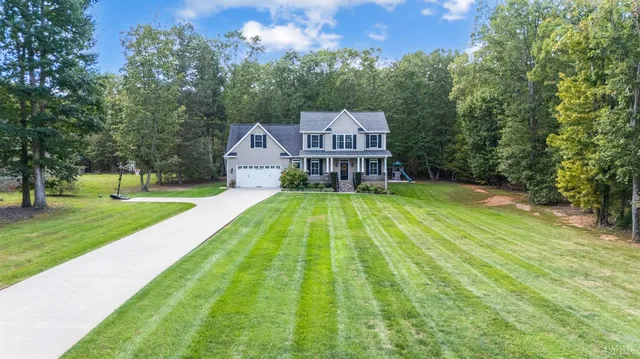 a view of a house with a big yard potted plants and large tree