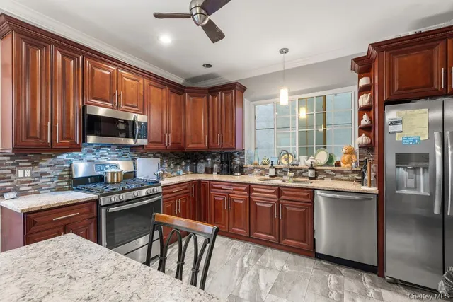 a kitchen with stainless steel appliances granite countertop wooden cabinets a sink dishwasher a stove and a refrigerator with wooden floor