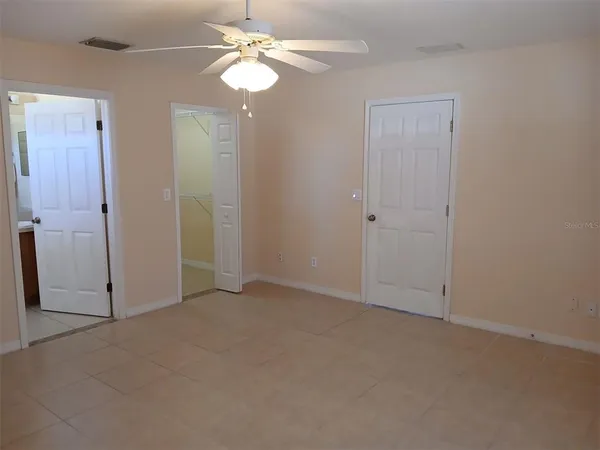 an empty room with closet and a ceiling fan