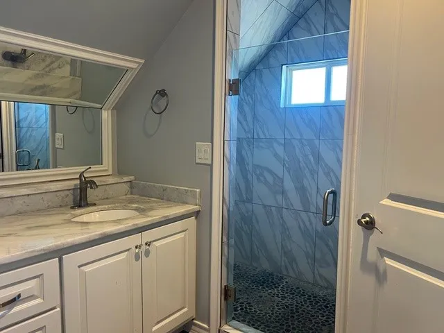 a bathroom with a granite countertop sink a mirror and shower