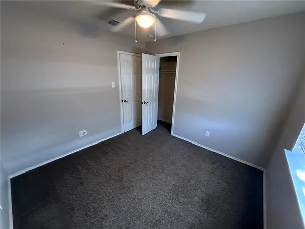 en empty room with windows and ceiling fan