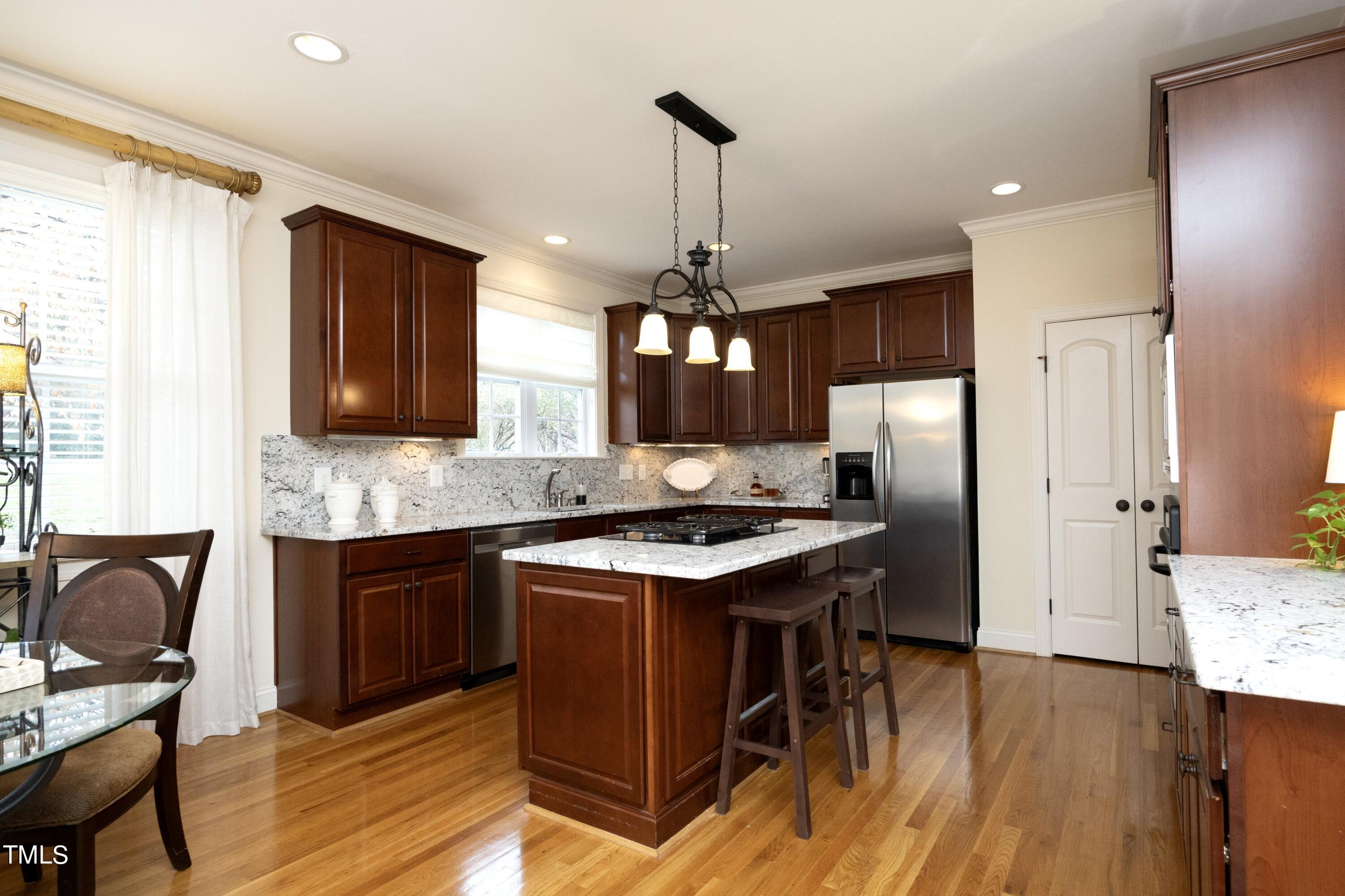 11514 Autumn Oaks Lane Raleigh, NC 27614 - Photo 15 of 39 a kitchen with stainless steel appliances granite countertop a stove refrigerator a sink dishwasher a dining table and chairs with wooden floor