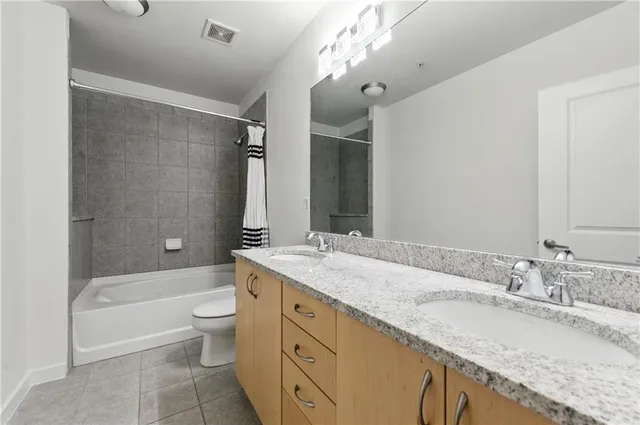 a bathroom with a granite countertop bathtub shower sink vanity mirror and toilet