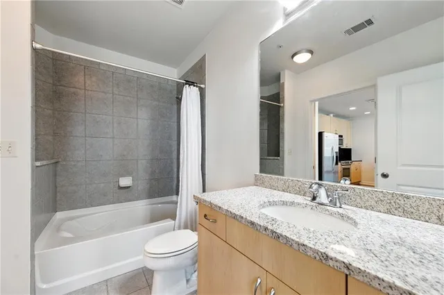 a bathroom with a granite countertop sink a toilet and bathtub