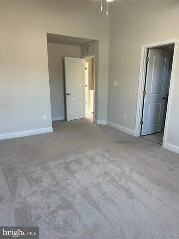 a view of an empty room with closet and mirror