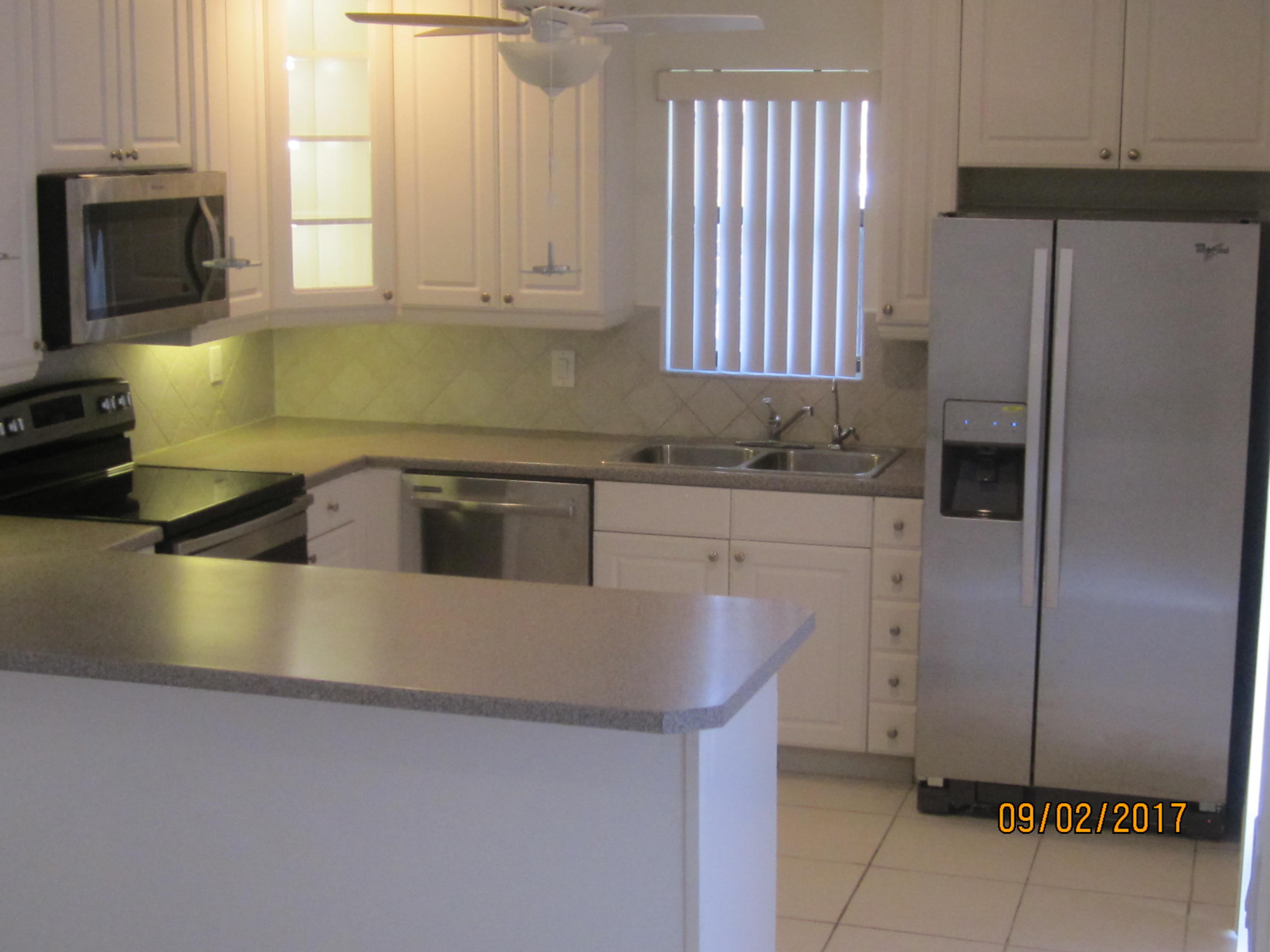 7515 Courtyard Run East Boca Raton, FL 33433 - Photo 4 of 16 a kitchen with stainless steel appliances granite countertop a sink a microwave a refrigerator and a stove