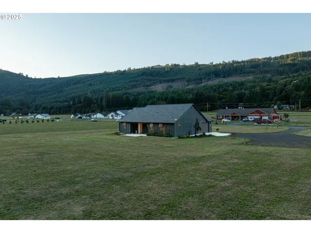 a view of a big house with a big yard and large trees