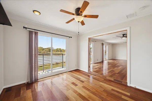 a view of an empty room with a window and wooden floor