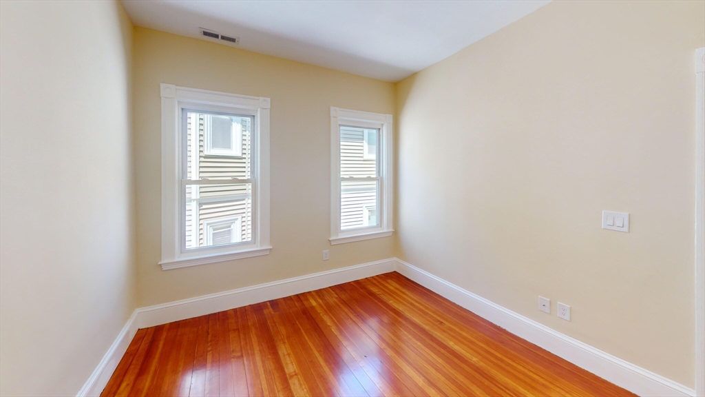 27 Champney Street, Unit 2 Boston, MA 02135 - Photo 11 of 12 an empty room with wooden floor and windows