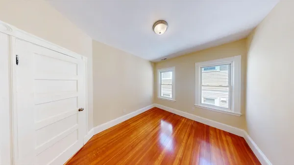 a view of empty room with window and wooden floor