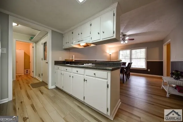 a kitchen with stainless steel appliances granite countertop a stove a sink dishwasher and white cabinets with wooden floor