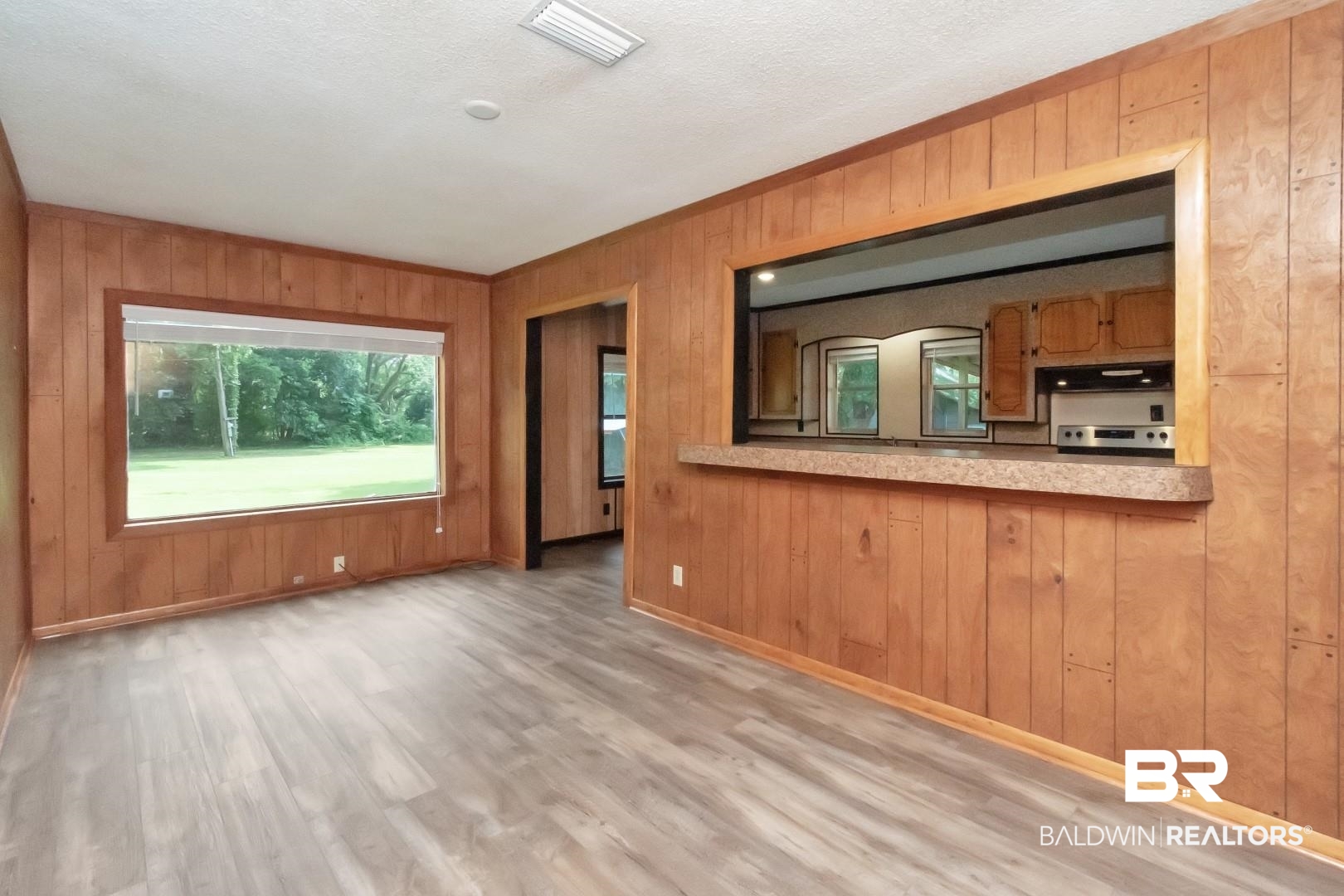 12751 Zanzibar Road Grand Bay, AL 36541 - Photo 8 of 30 Unfurnished living room with wood walls, light wood-type flooring, and a textured ceiling