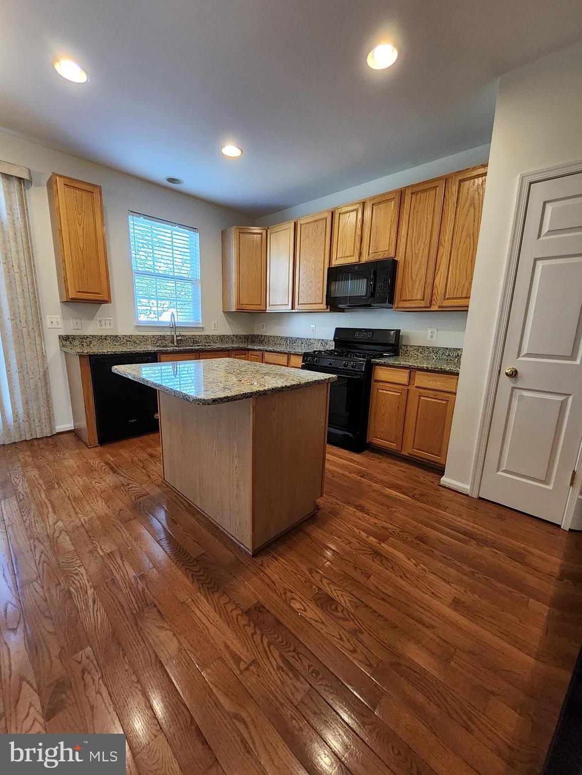 20939 Calais Terrace Ashburn, VA 20147 - Photo 3 of 31 a kitchen with stainless steel appliances granite countertop a sink a stove a refrigerator cabinets and wooden floor