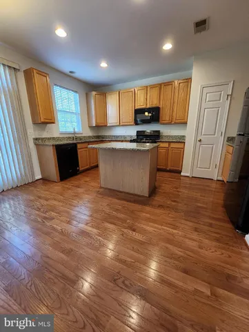 a large kitchen with stainless steel appliances wooden floors and wooden cabinets