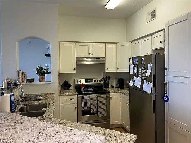 a kitchen with stainless steel appliances granite countertop a refrigerator stove top oven and a sink