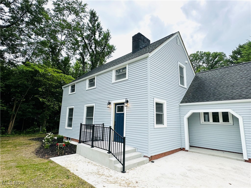 568 North Road Southeast Warren, OH 44484 - Photo 2 of 49 Front view of property featuring a chimney, an attached garage, a shingled roof, and concrete driveway