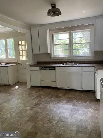 a kitchen with granite countertop a sink and white cabinets