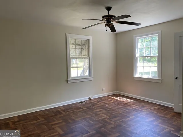 a view of empty room with wooden floor and fan