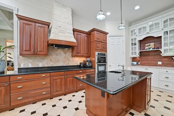 a kitchen with stainless steel appliances granite countertop a sink a stove and a wooden cabinets