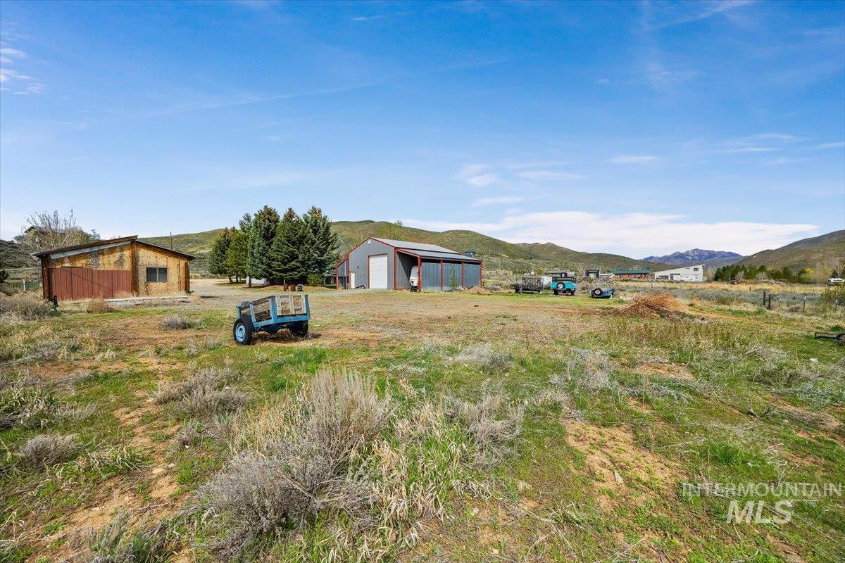 102 Willow Creek Road Fairfield, ID 83327 - Photo 27 of 32 View of yard featuring an outbuilding, a mountain view, a detached garage, and a view of countryside