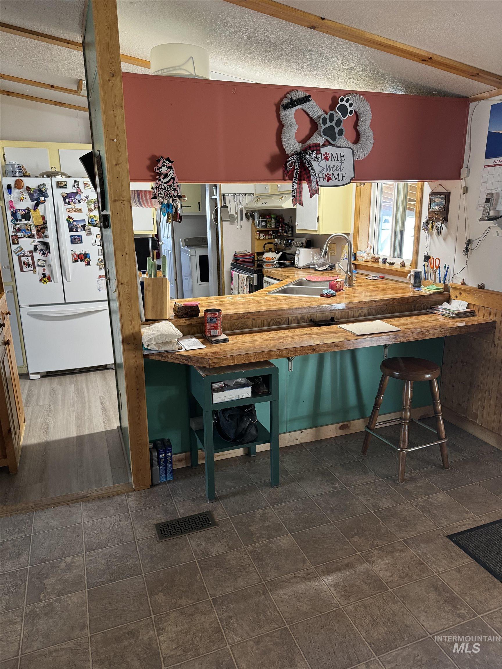 102 Willow Creek Road Fairfield, ID 83327 - Photo 37 of 40 Kitchen with freestanding refrigerator, stainless steel electric stove, a textured ceiling, a breakfast bar, and light countertops
