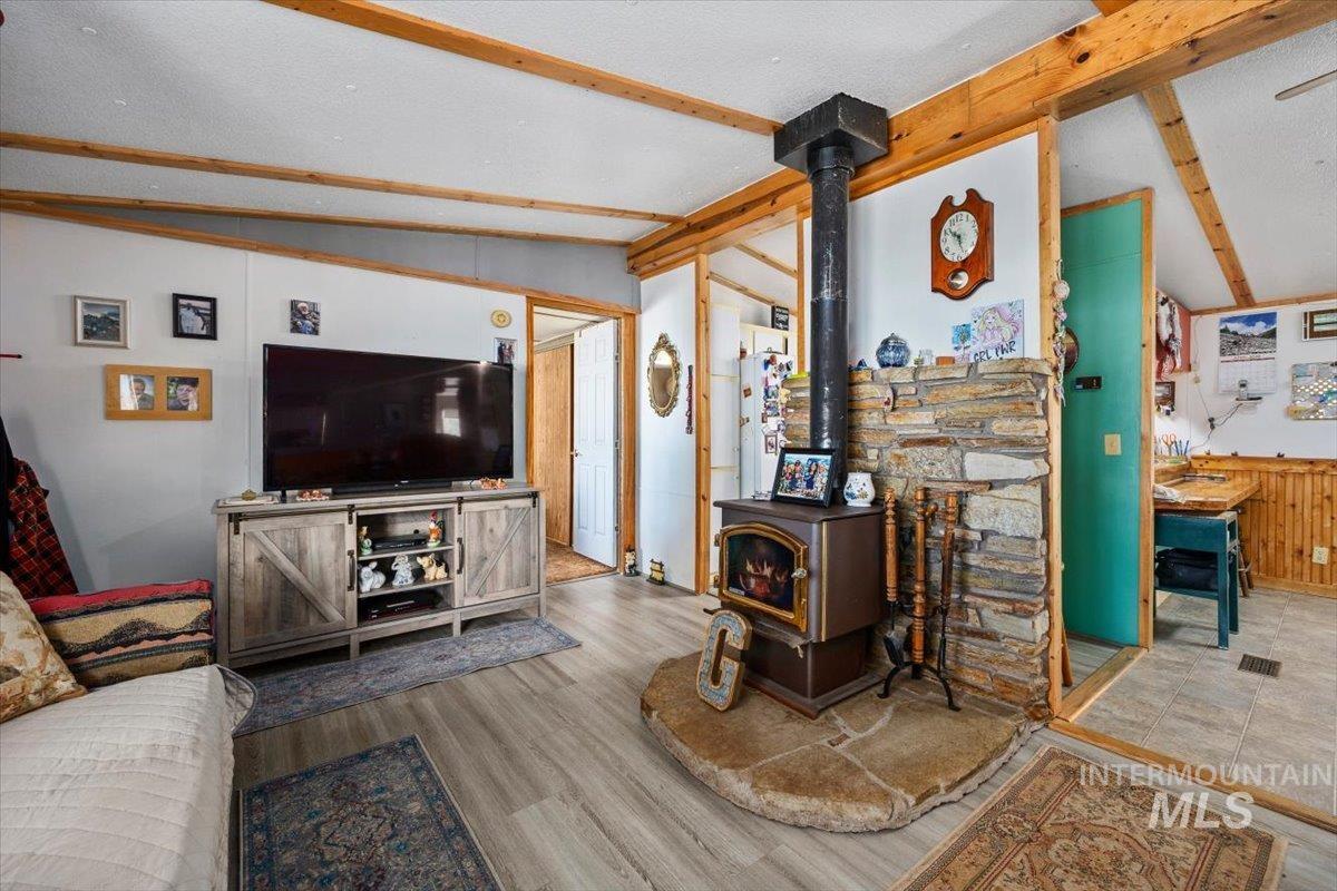 102 Willow Creek Road Fairfield, ID 83327 - Photo 8 of 32 Living area with lofted ceiling with beams, a wood stove, and wood finished floors