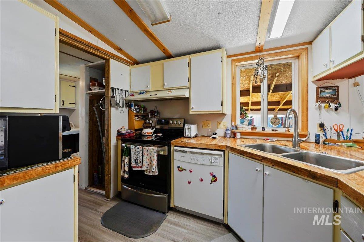 102 Willow Creek Road Fairfield, ID 83327 - Photo 10 of 32 Kitchen featuring stainless steel electric stove, dishwasher, black microwave, light wood-type flooring, and a textured ceiling