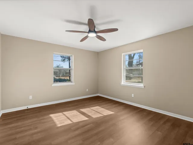 a view of a big room with wooden floor and windows