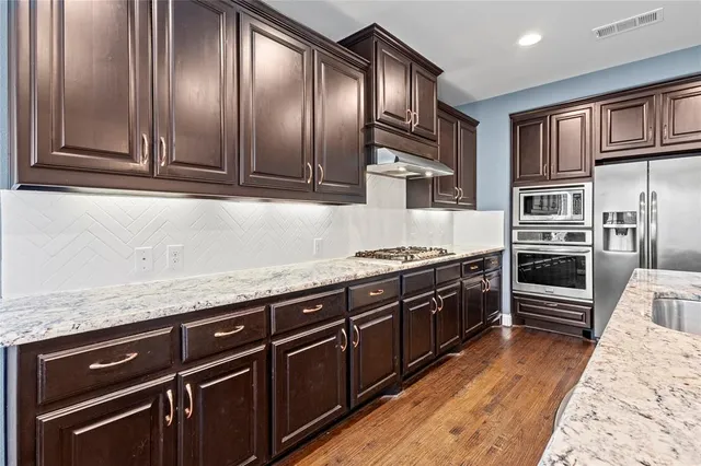a kitchen with stainless steel appliances granite countertop a refrigerator a sink dishwasher stove and oven
