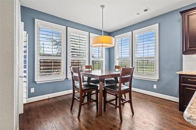 a dining room with wooden floor a chandelier a glass table and chairs