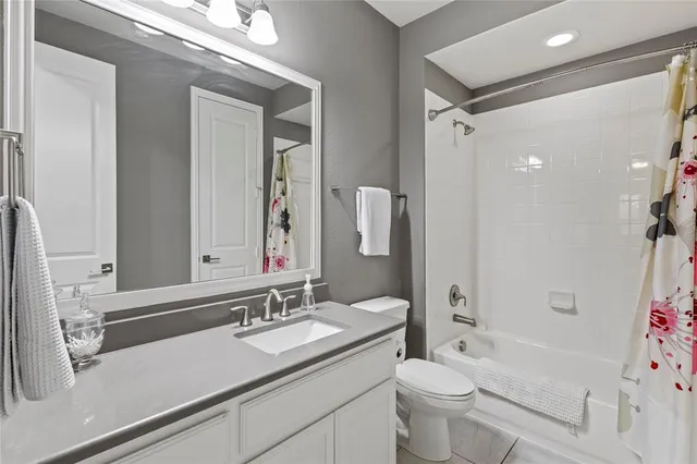 a bathroom with a granite countertop sink a toilet a mirror a vanity and shower